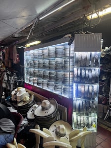 Vitrina iluminada con cinturones enrollados en filas y pilas de sombreros de palma y fieltro delante